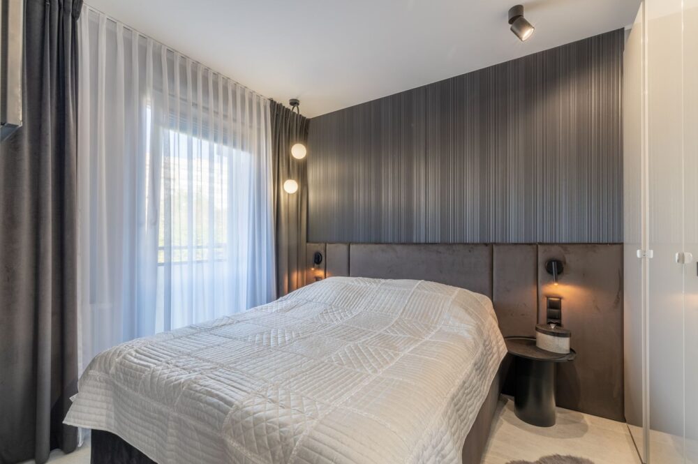 Helles Schlafzimmer mit bodentiefem Fenster und Blick ins Grüne – Wohnung in Swinemünde