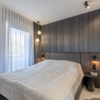 Helles Schlafzimmer mit bodentiefem Fenster und Blick ins Grüne – Wohnung in Swinemünde