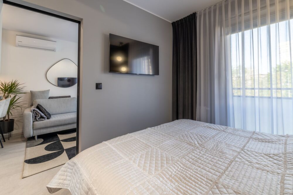 Schlafzimmer mit TV, Klimaanlage und Vorhängen – 2-Zimmer-Wohnung nahe Ostsee