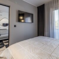 Schlafzimmer mit TV, Klimaanlage und Vorhängen – 2-Zimmer-Wohnung nahe Ostsee
